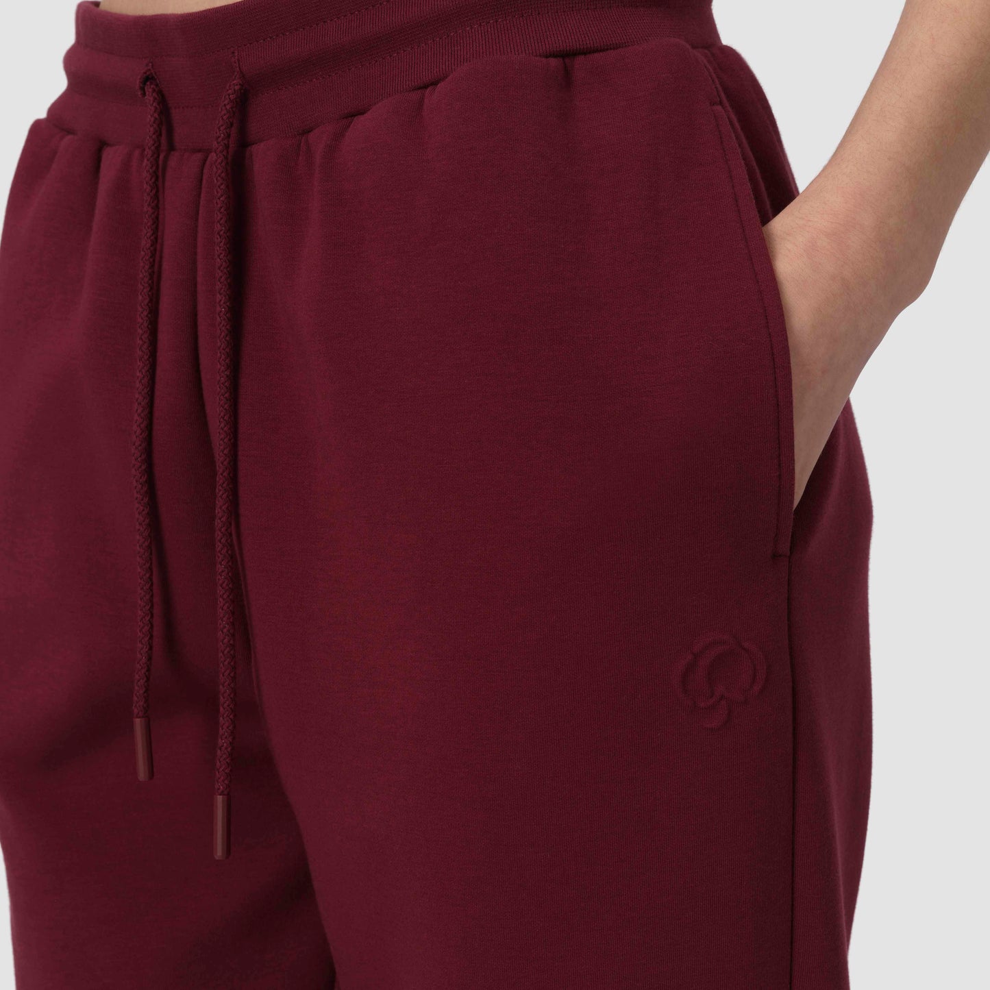 Close up of burgundy jogger with drawstring and embossed cotton flower