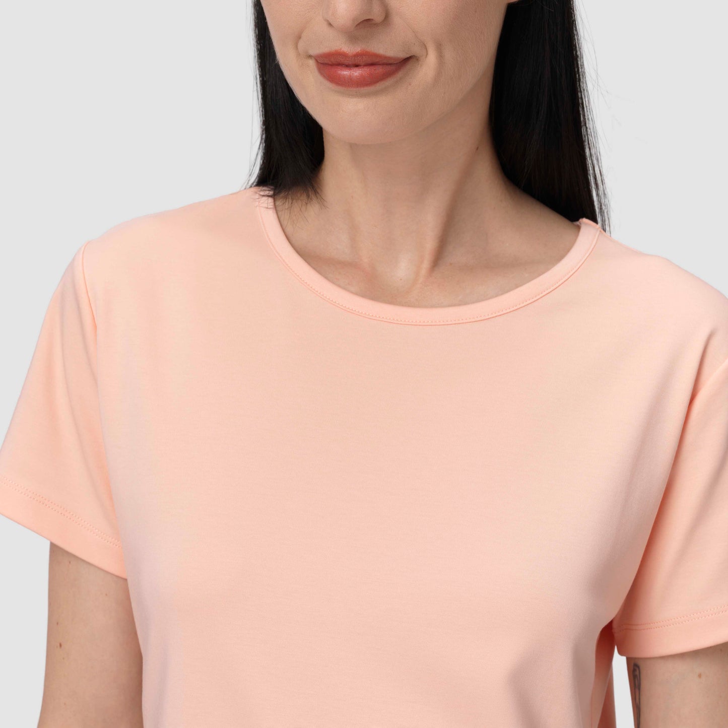Woman wearing a light pink t-shirt against a plain background