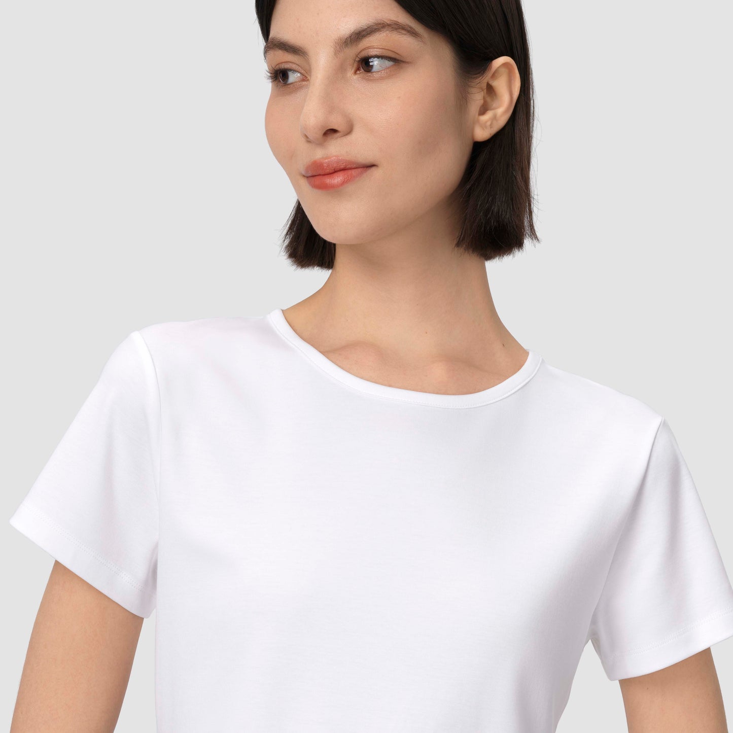 Une personne vêtue d'un t-shirt blanc uni sur fond gris clair