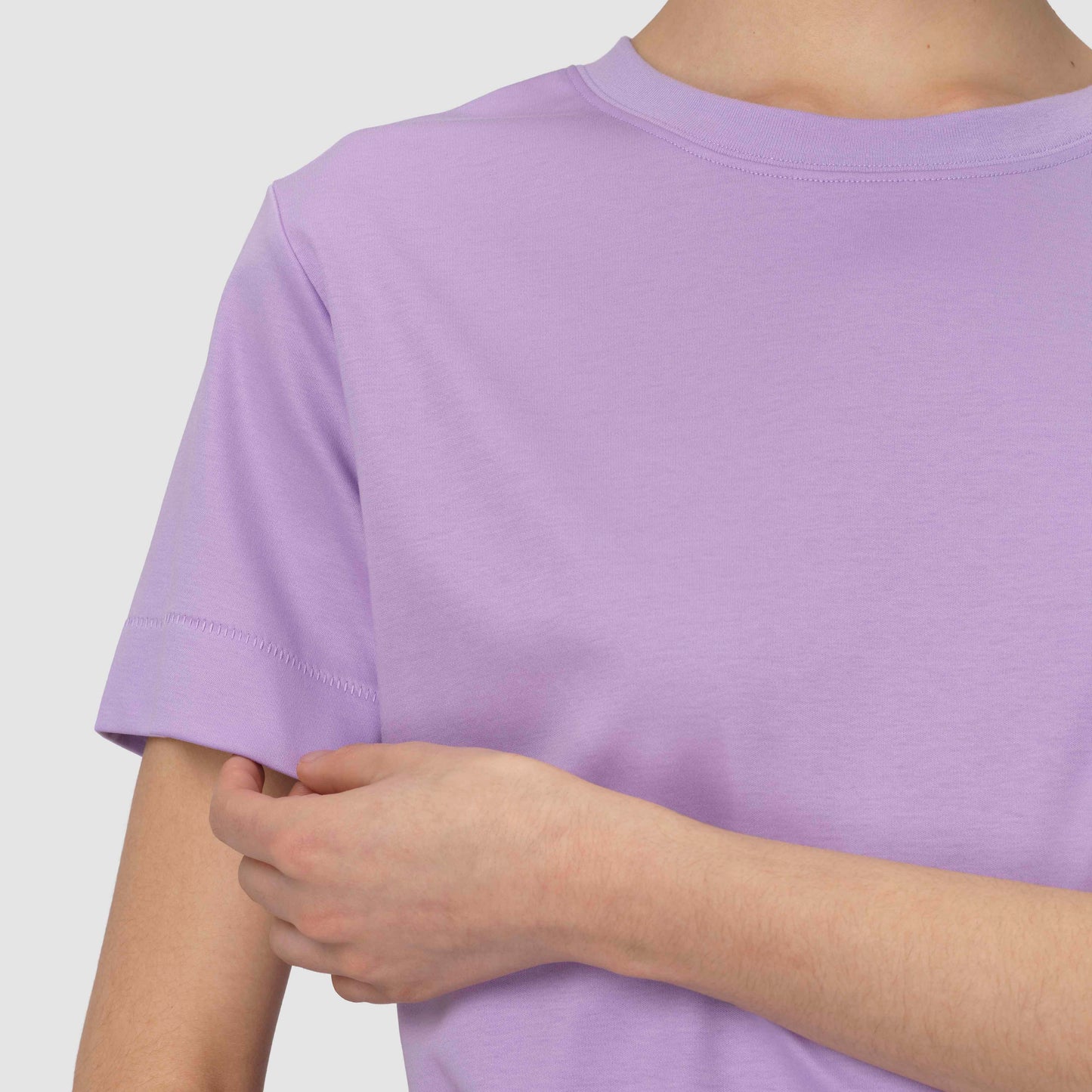 Person wearing a plain light purple t-shirt against a white background