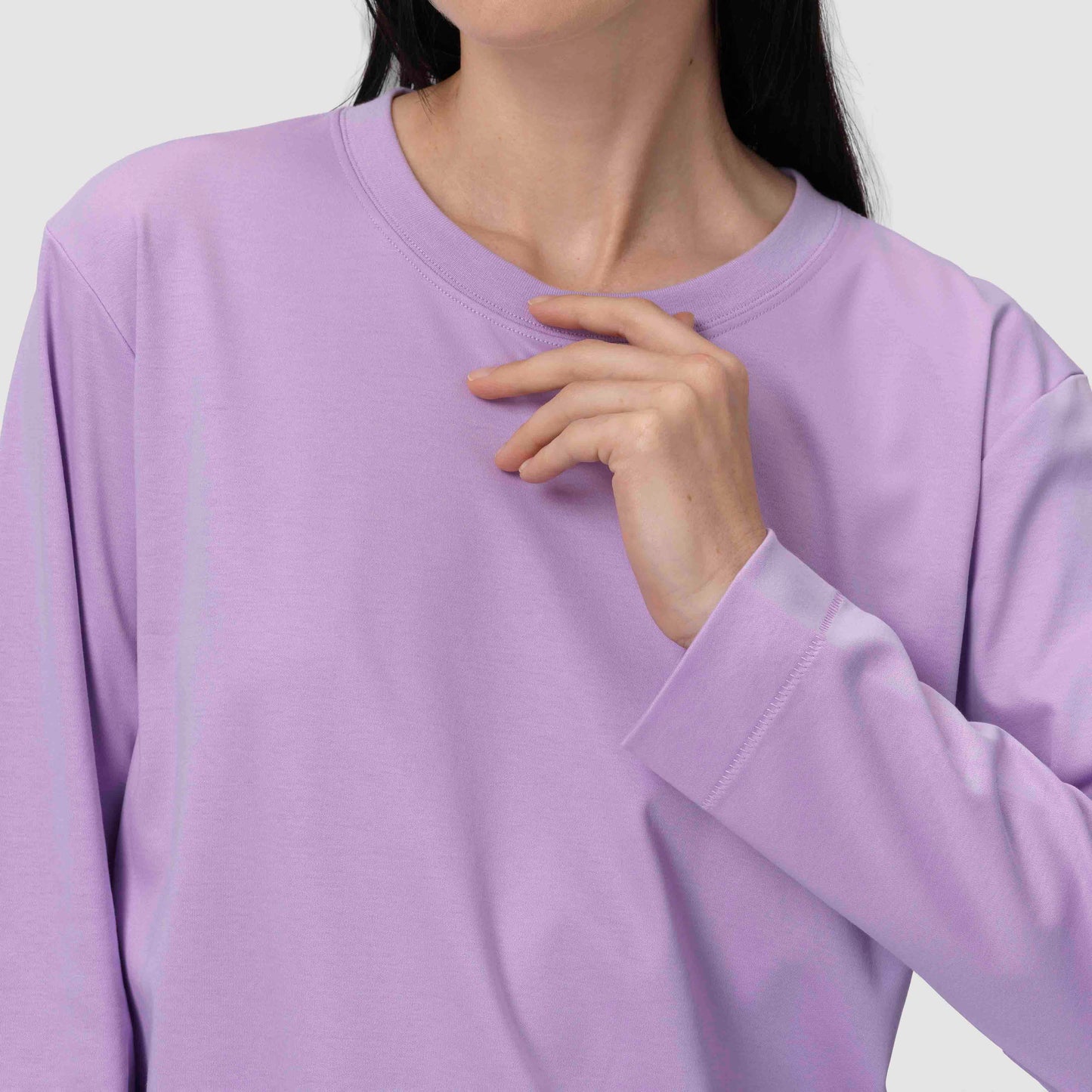 Une personne portant un sweat-shirt violet clair sur un fond neutre