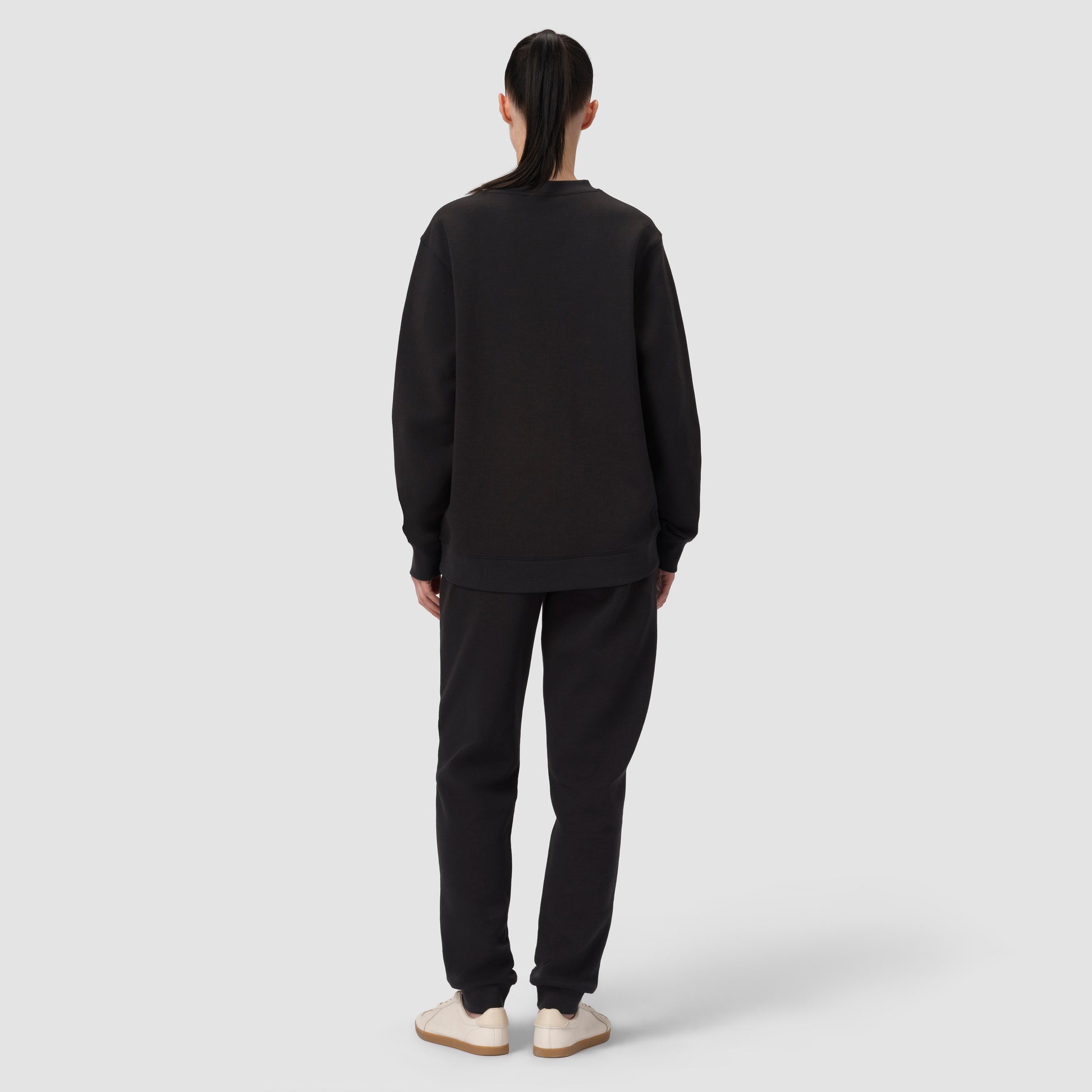 Person wearing a black sweatshirt and pants set on a white background
