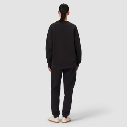 Person wearing a black sweatshirt and pants set on a white background