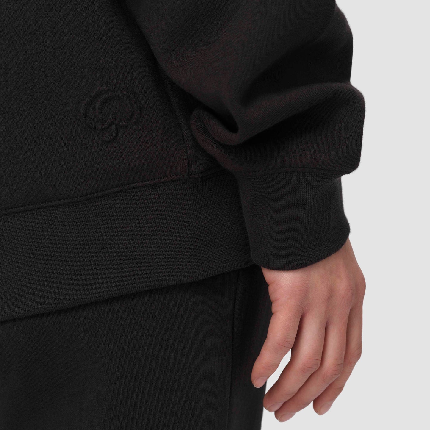 Black hoodie with a brand logo against a light gray background