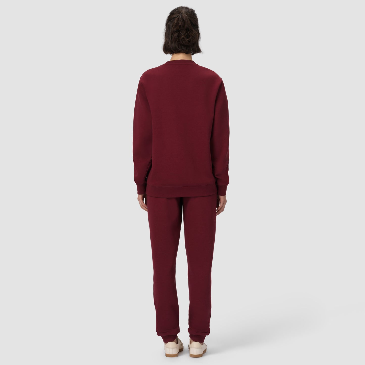 Une personne vêtue d'un survêtement bordeaux sur fond blanc