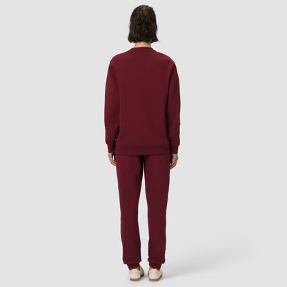 Une personne vêtue d'un survêtement bordeaux sur fond blanc