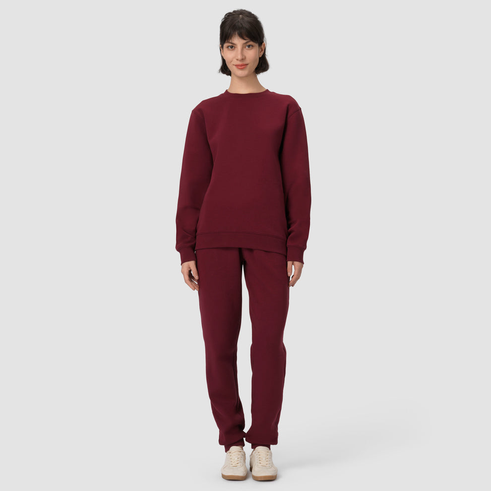 Une personne vêtue d'un sweat-shirt et d'un pantalon bordeaux sur fond blanc