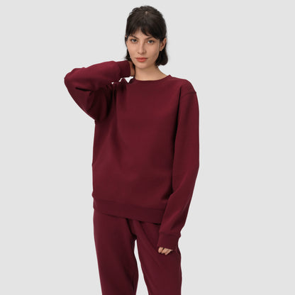 Une personne vêtue d'un sweat-shirt et d'un pantalon bordeaux sur un fond gris clair