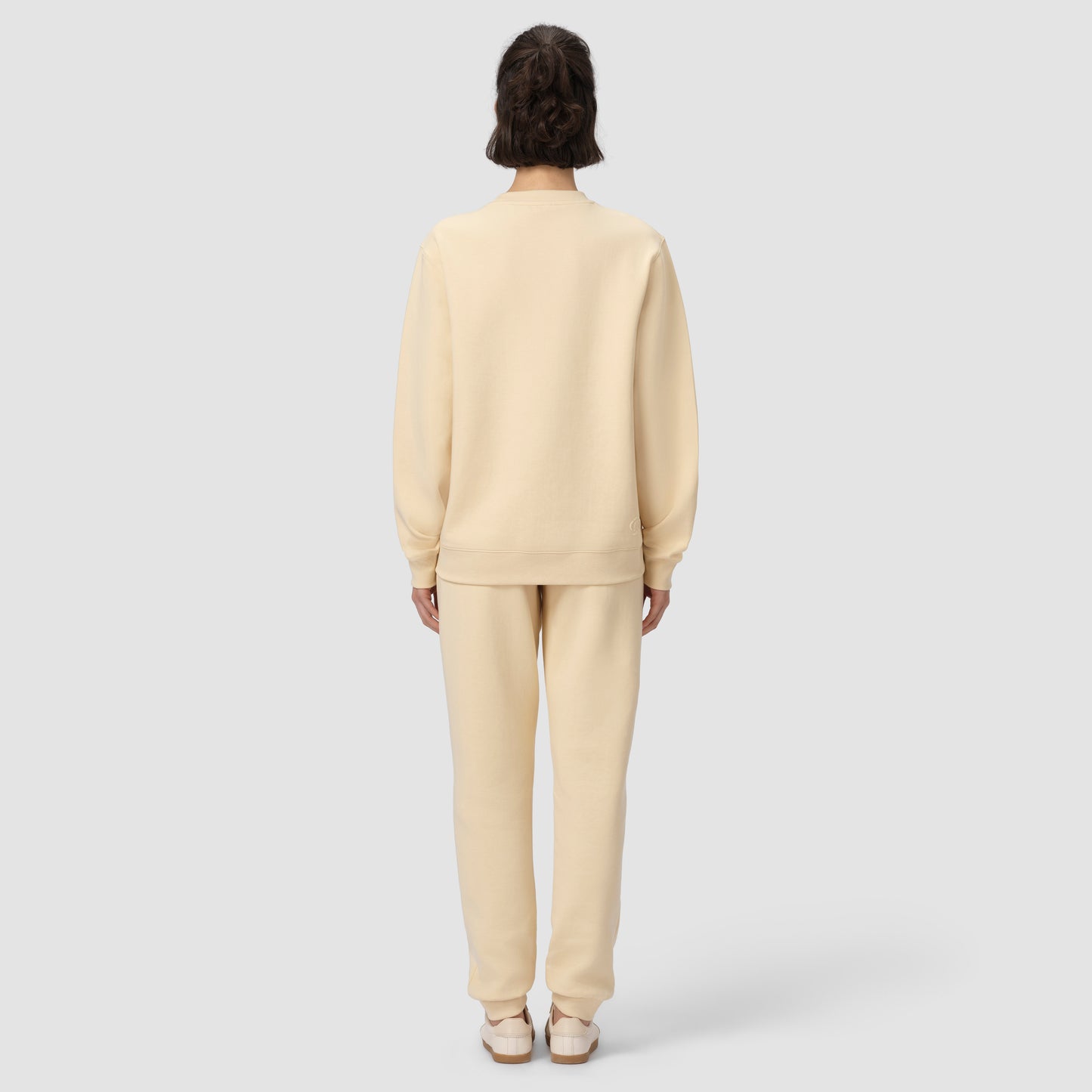 Back of model wearing cream loungewear set on plain background