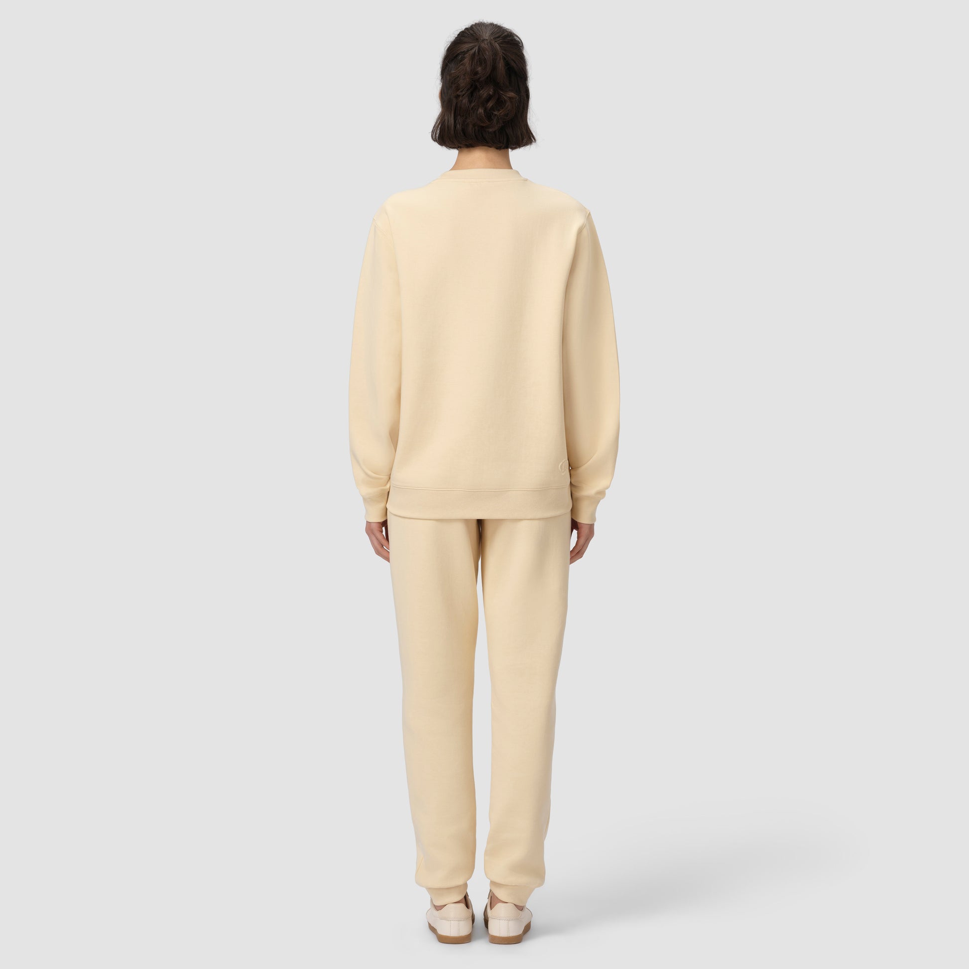 Back of model wearing cream loungewear set on plain background