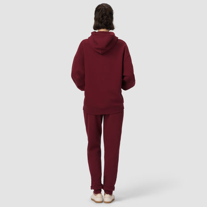 Person wearing a burgundy hoodie and pants on a white background