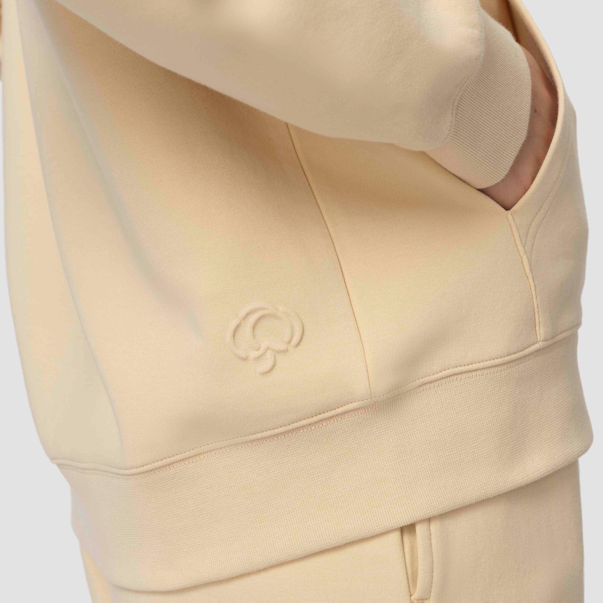 Sweat à capuche crème avec un logo sur fond blanc