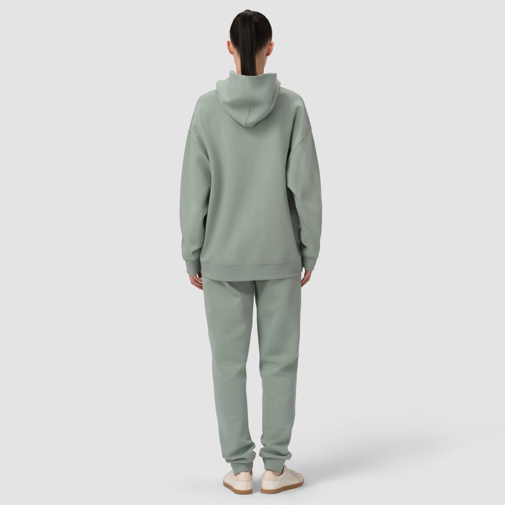 Person wearing a light green hoodie and pants on a white background