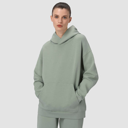 Person wearing a light green hoodie and pants on a plain background