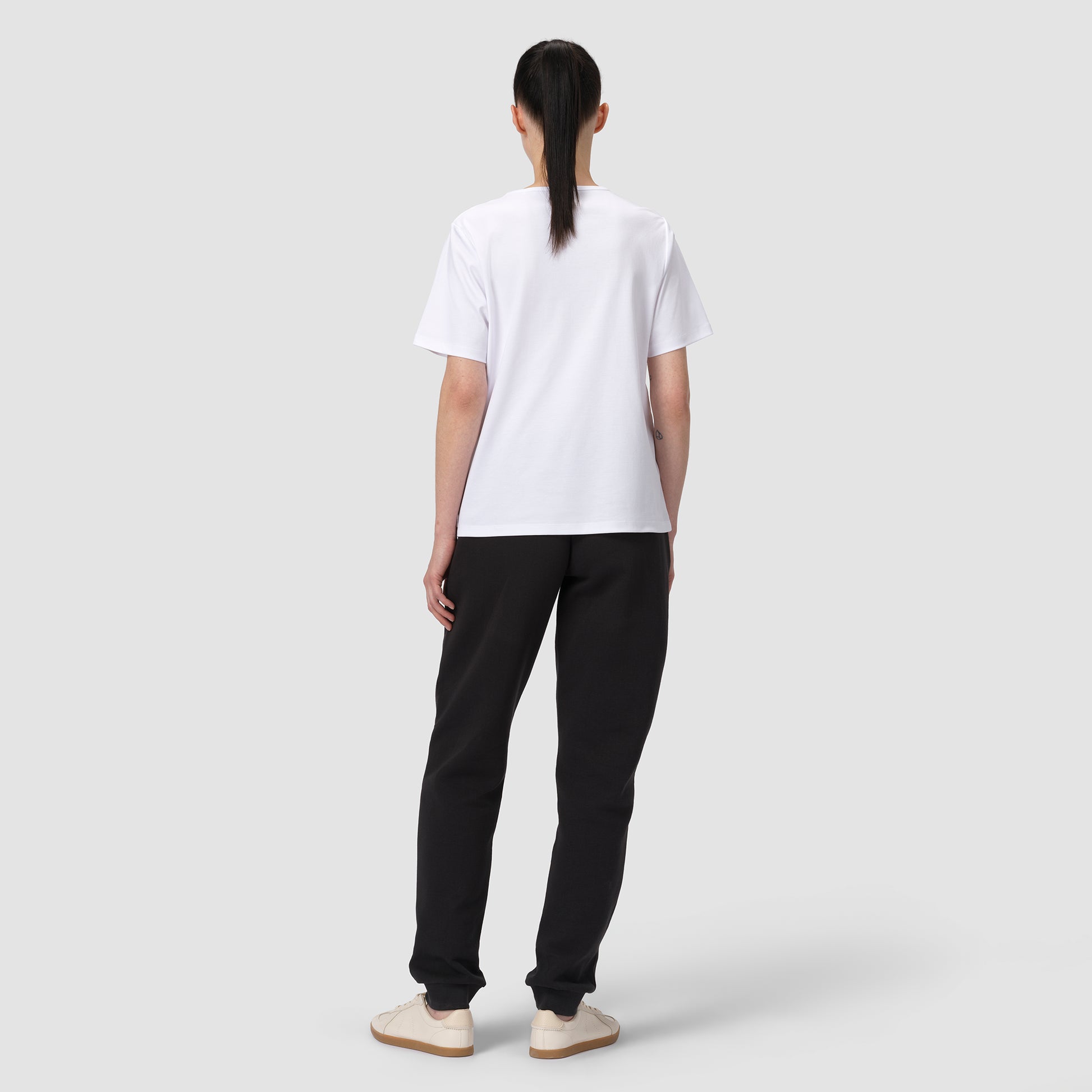 Person wearing a white t-shirt and black pants on a plain background