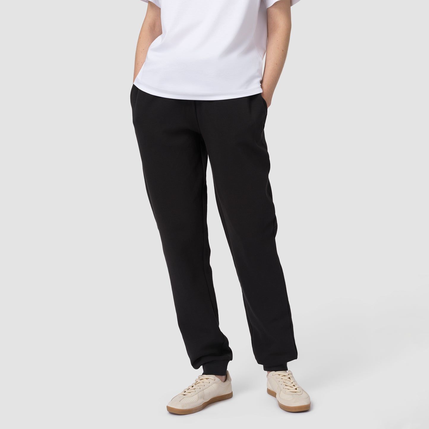 Person wearing black pants and a white shirt on a plain background