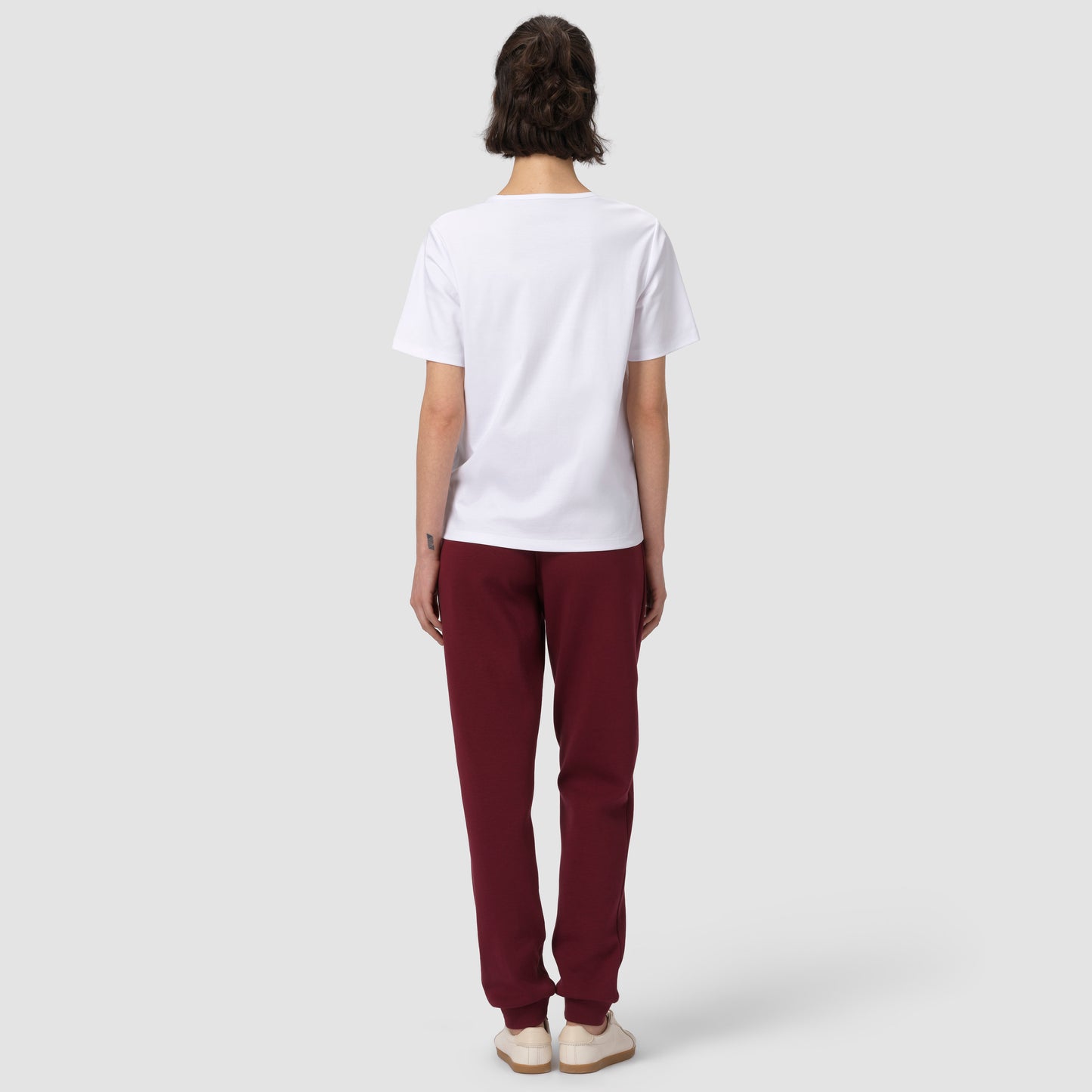 Back of model wearing burgundy jogger with white tee and shoes