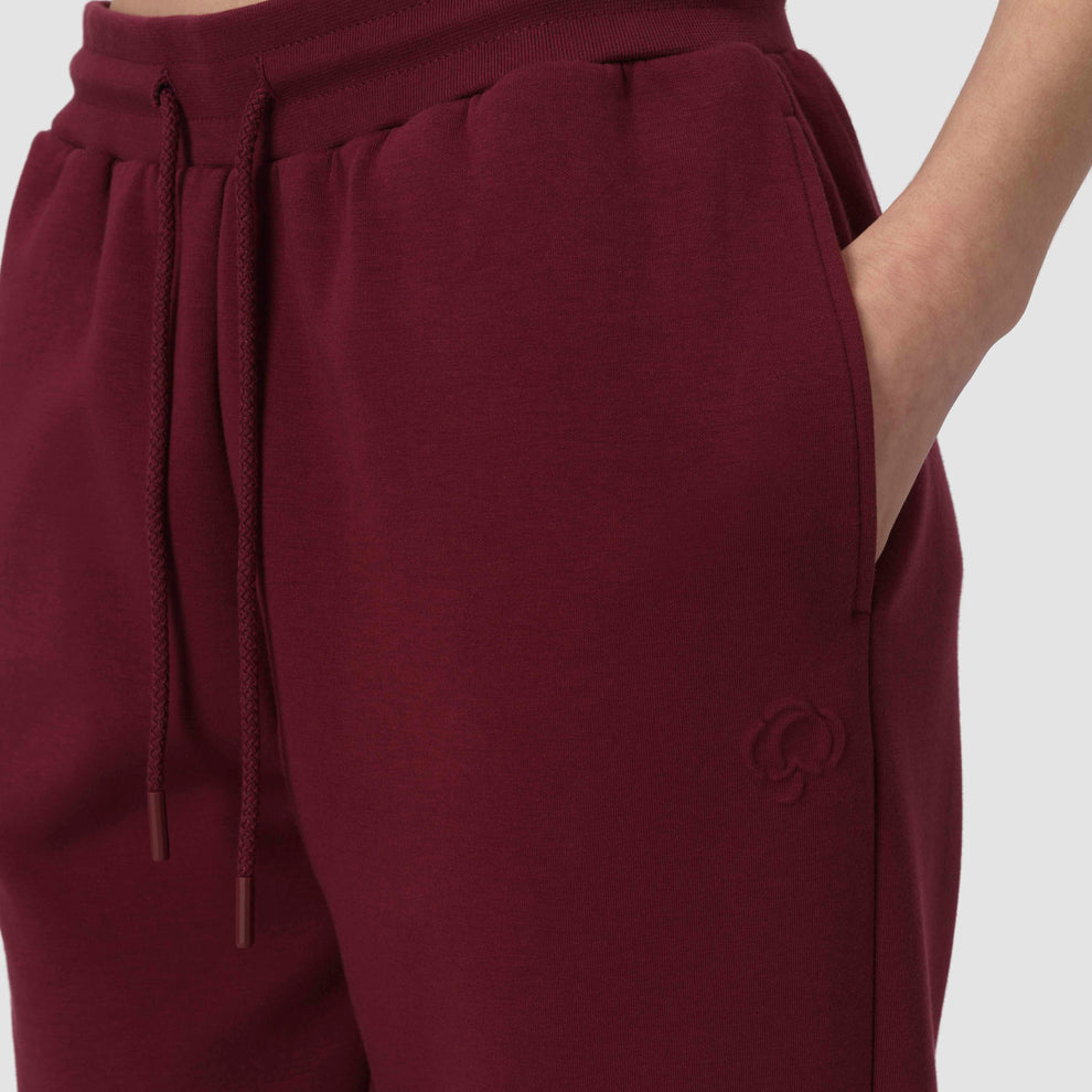 Gros plan sur un pantalon de jogging bordeaux avec cordon de serrage et fleur en coton en relief