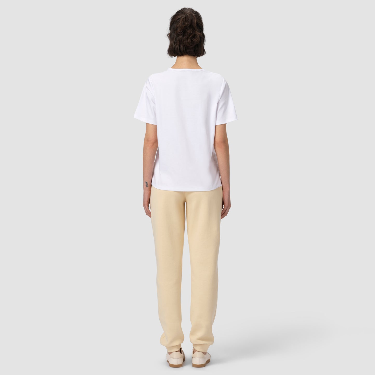 Back of model wearing cream jogger with white tee and shoes 