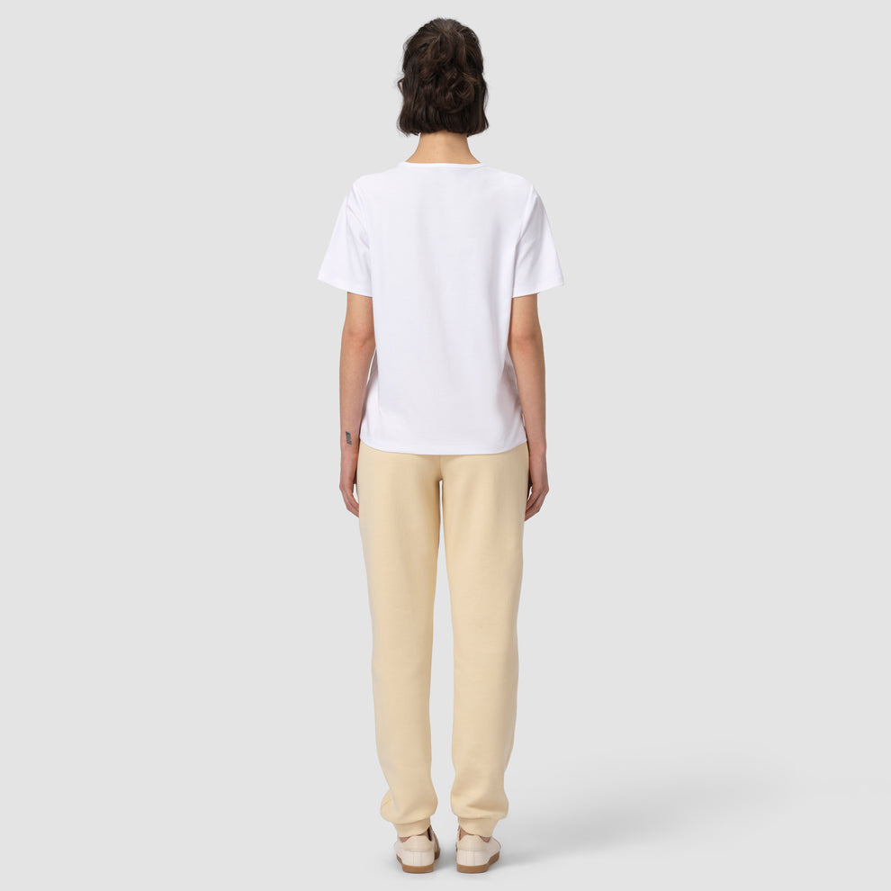 Vue de dos du mannequin portant un pantalon de jogging crème, un t-shirt blanc et des chaussures 