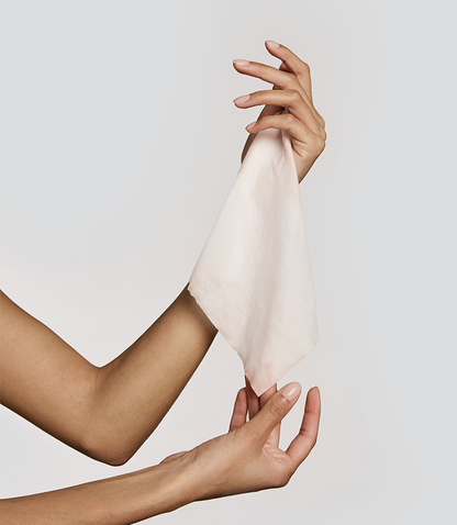 Hands holding a white cotton towelette wet against a plain background