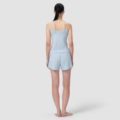 Back of a model wearing a light blue short pajama in plain background