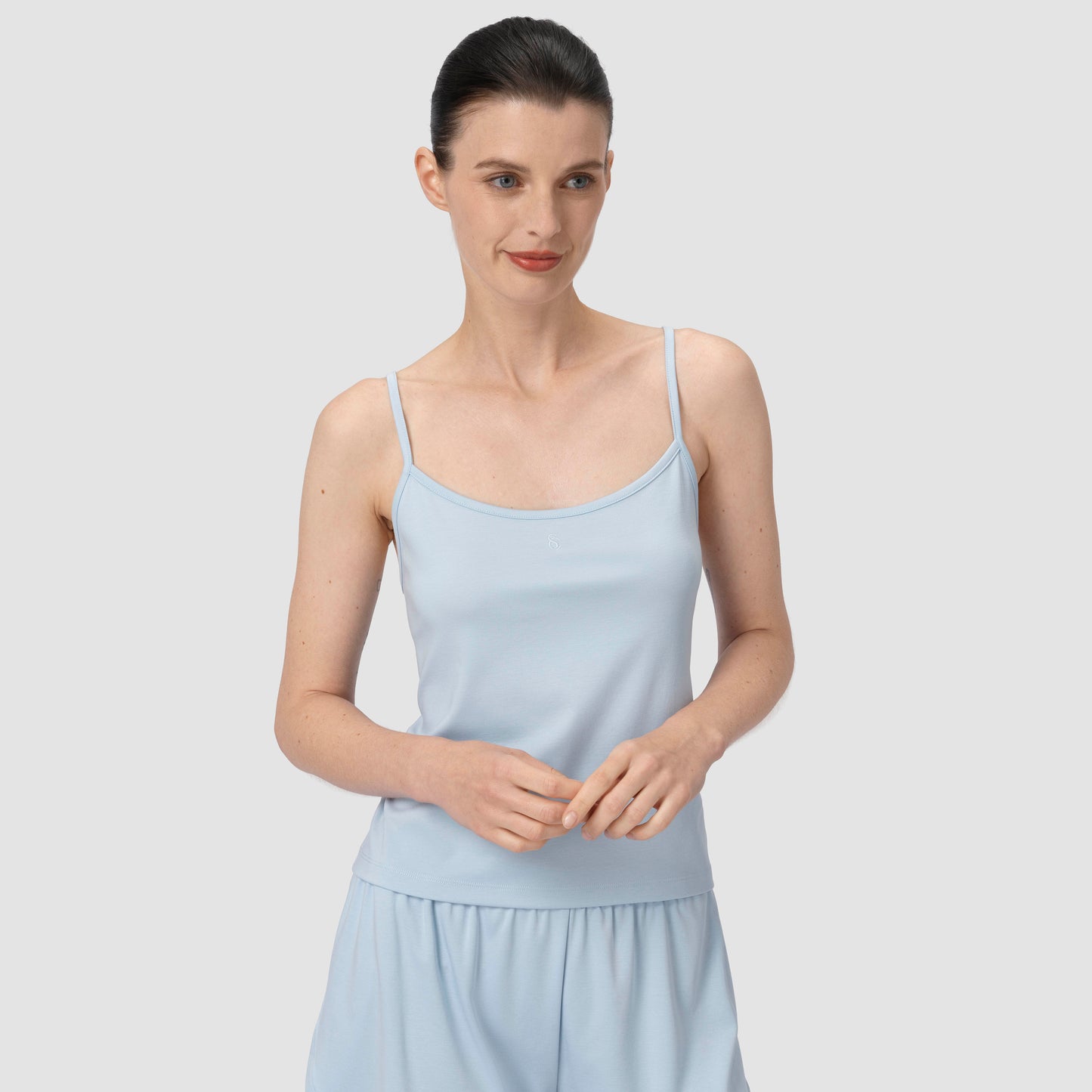 Model smiling wearing a light blue pajama in a plain backround