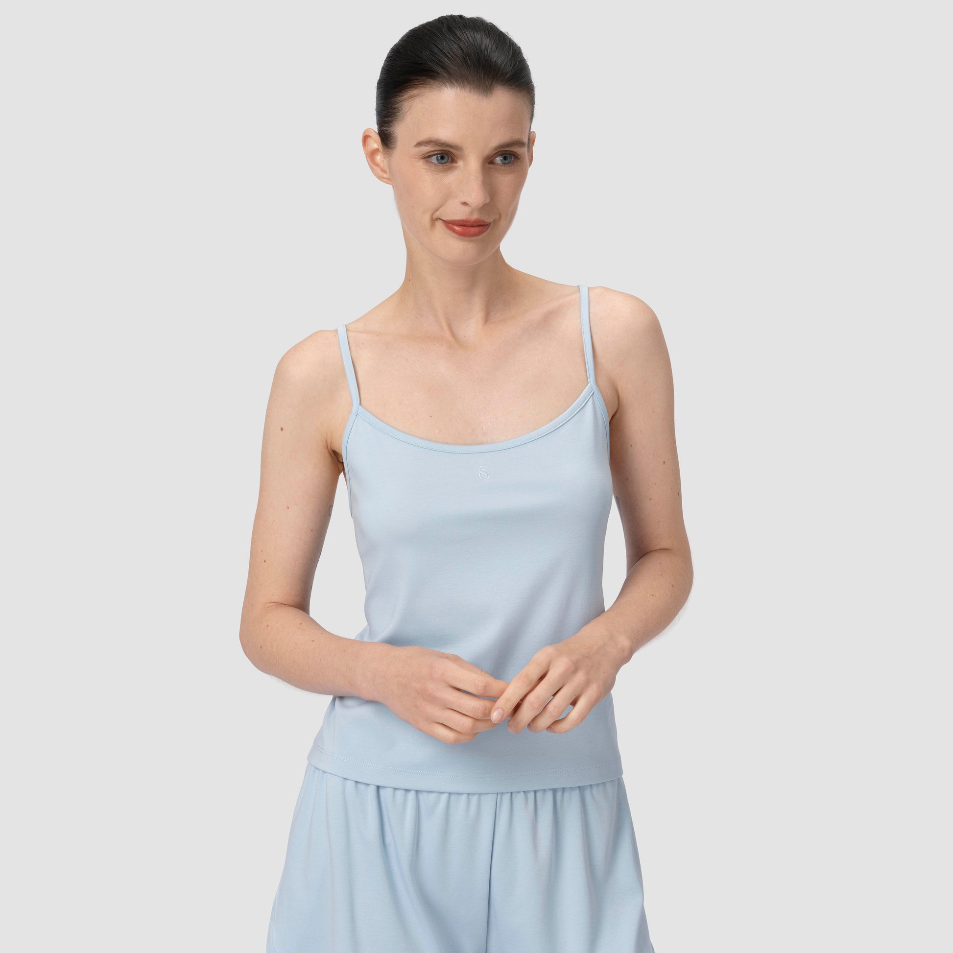 Model smiling wearing a light blue pajama in a plain backround