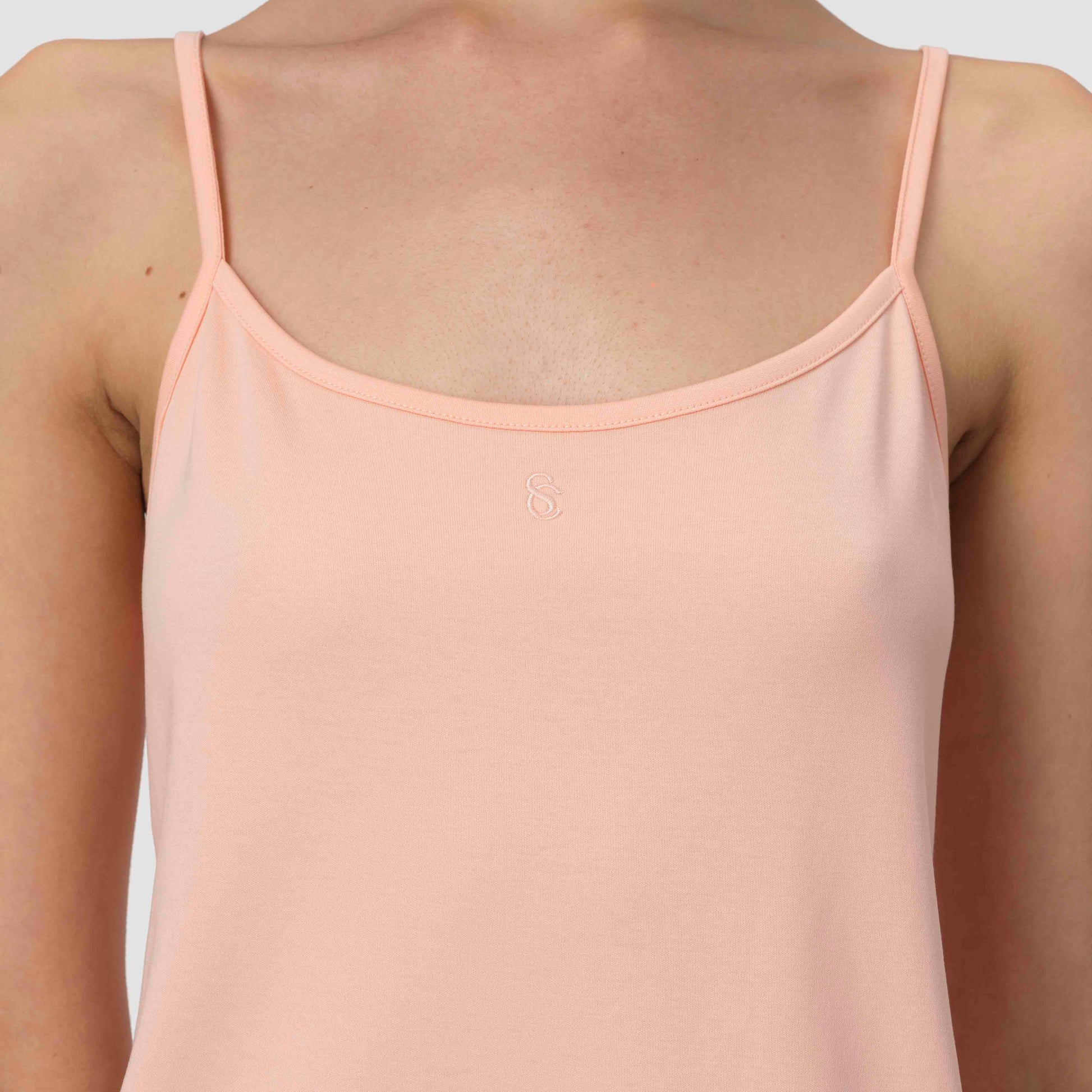 Light pink salmon camisole pajama worn by a person on a light gray background