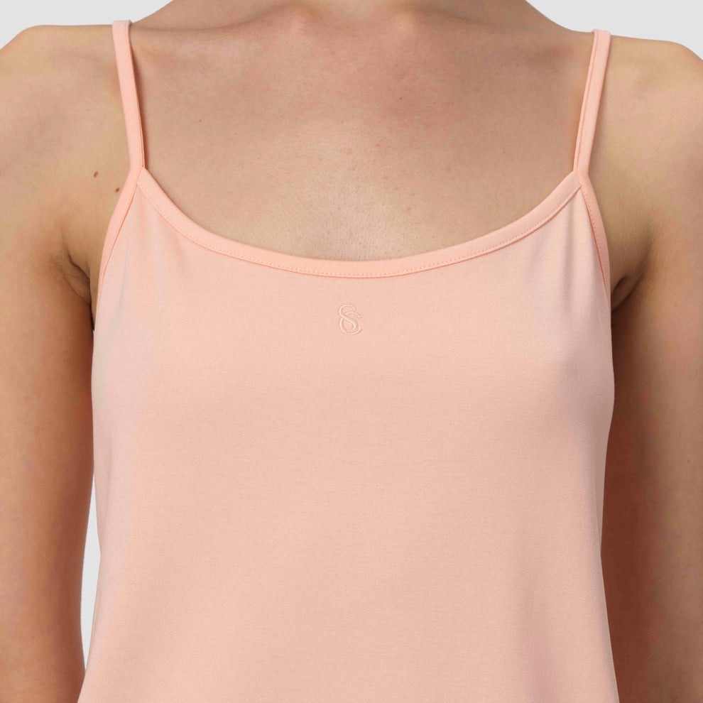 Un pyjama sans manches couleur saumon clair porté par une personne sur un fond gris clair