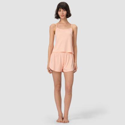 Woman wearing a light pink salmon pajama set on a white background