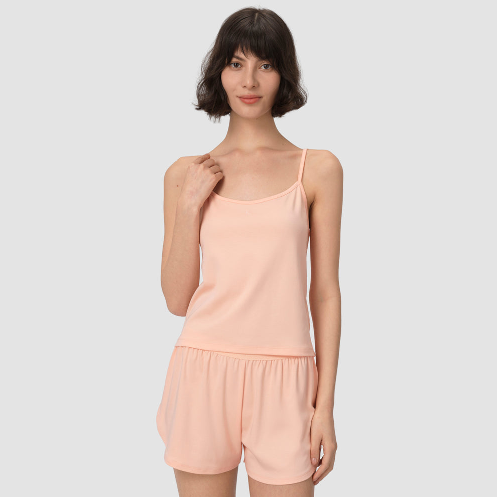 Une femme portant un ensemble short et chemisier couleur saumon clair sur fond uni