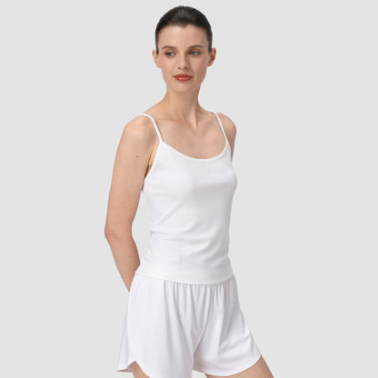Woman wearing a white tank top and shorts on a plain background