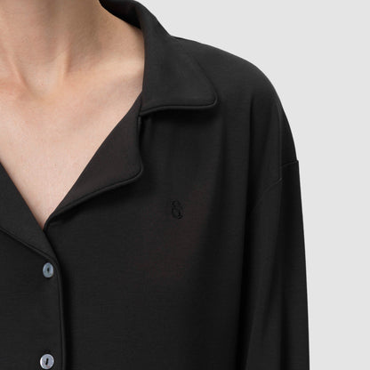 Close-up of a black shirt with a collar and buttons on a light gray background