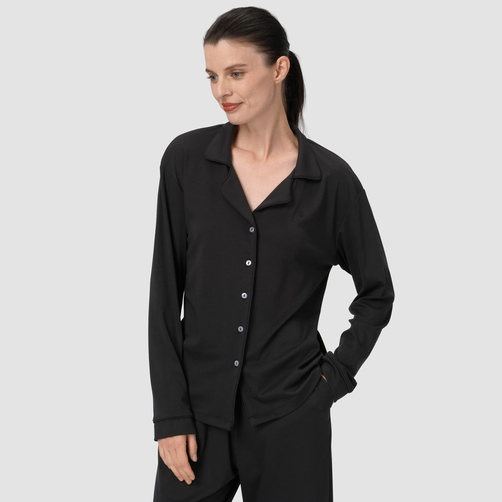 Woman wearing a black shirt with buttons on a plain background