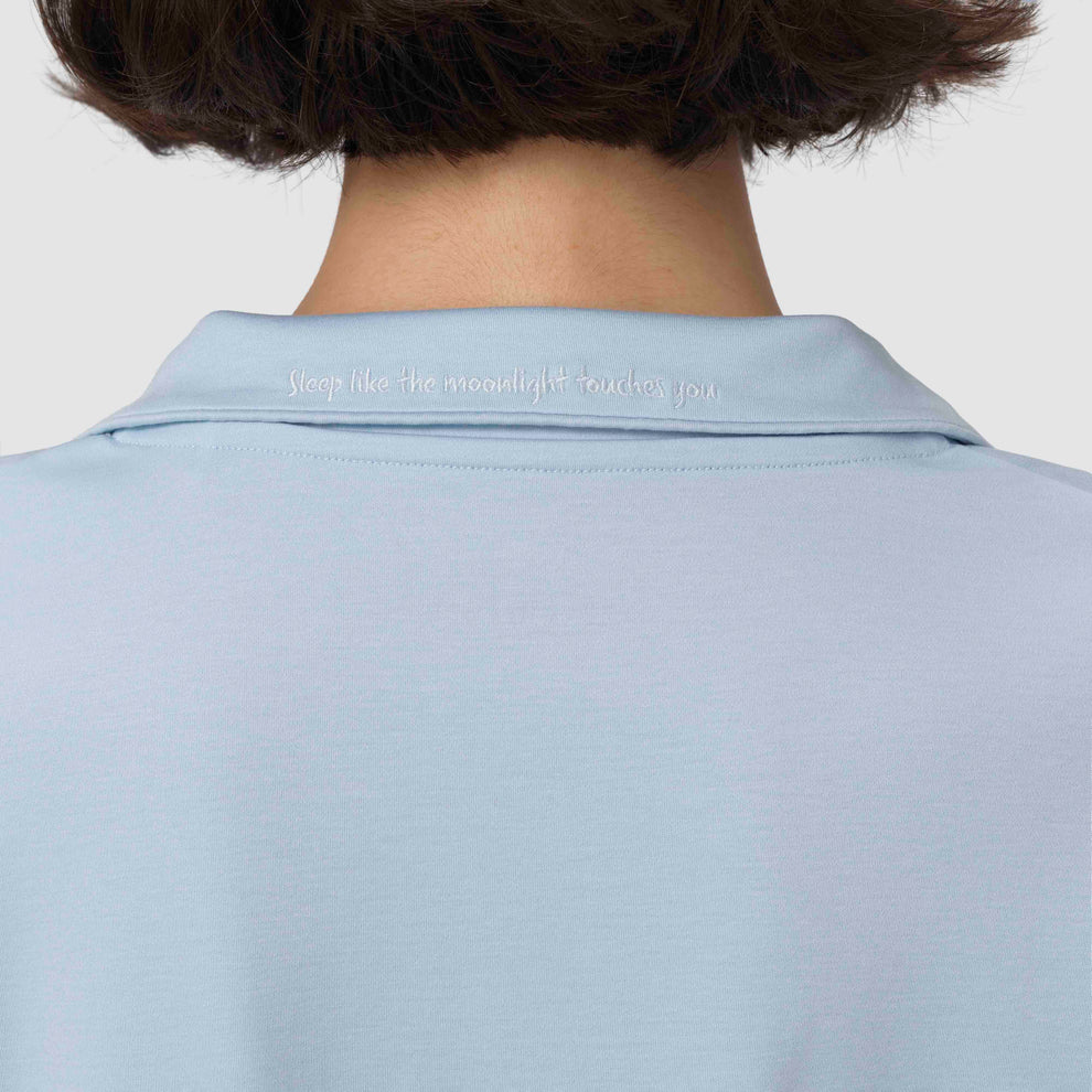 Pyjama bleu clair avec un texte sur le col, sur fond uni