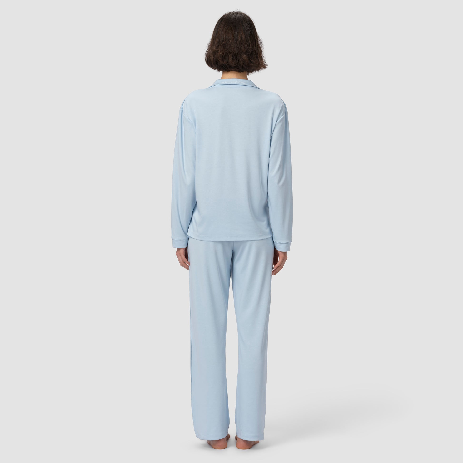 Person wearing a light blue pajama set on a white background