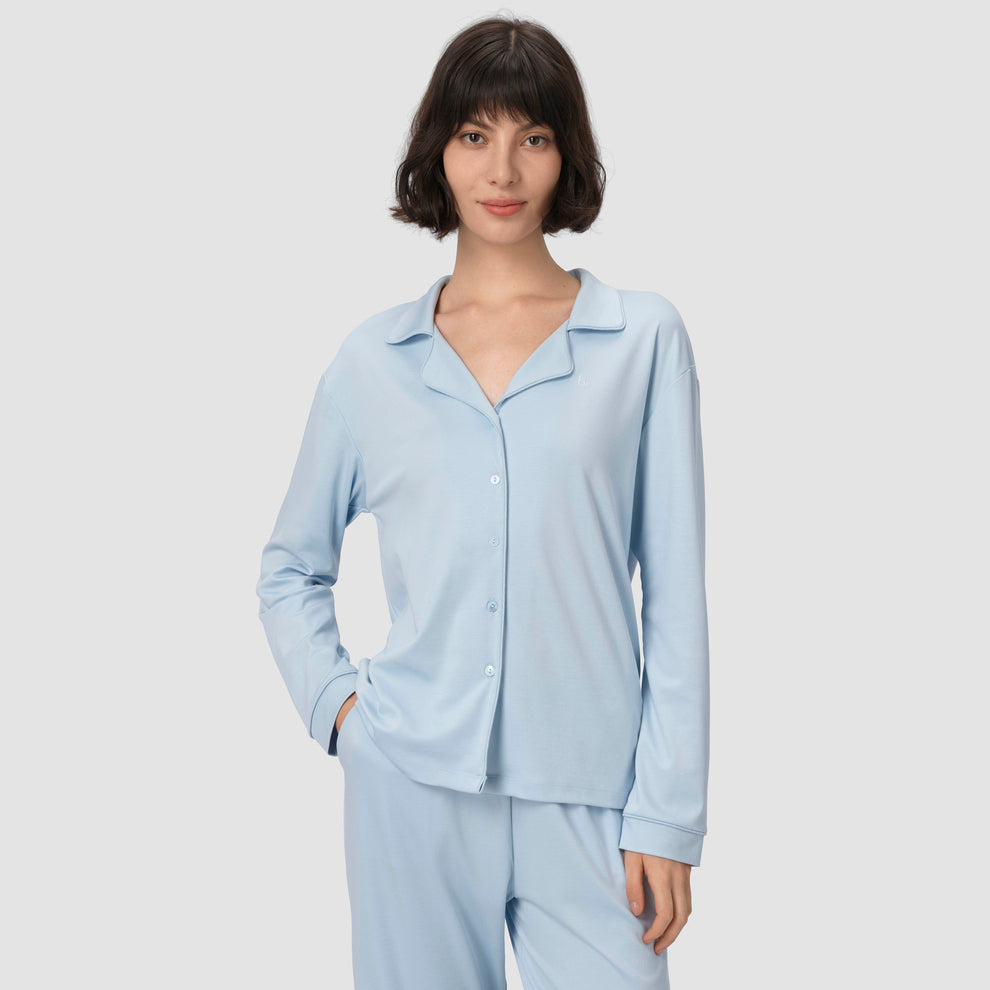 Une femme vêtue d'un pyjama bleu clair sur un fond uni