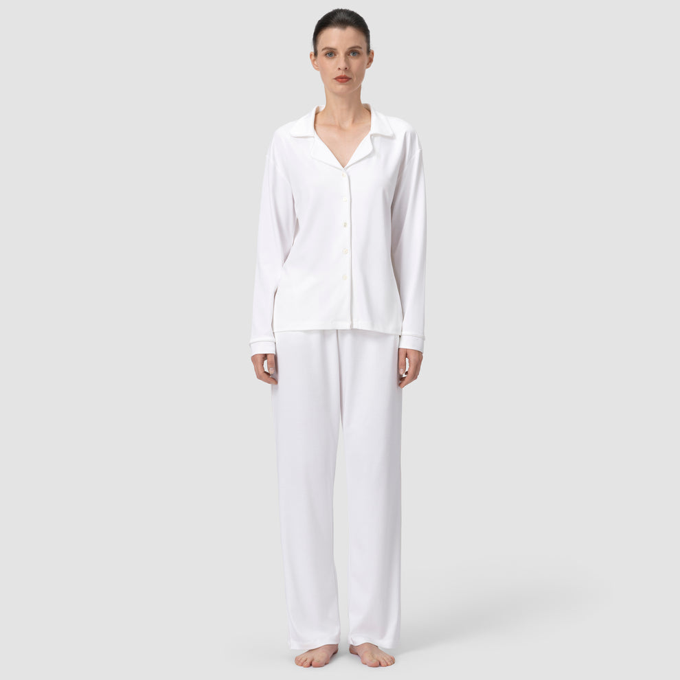 Front shot of white pajama with model stading still in plain background
