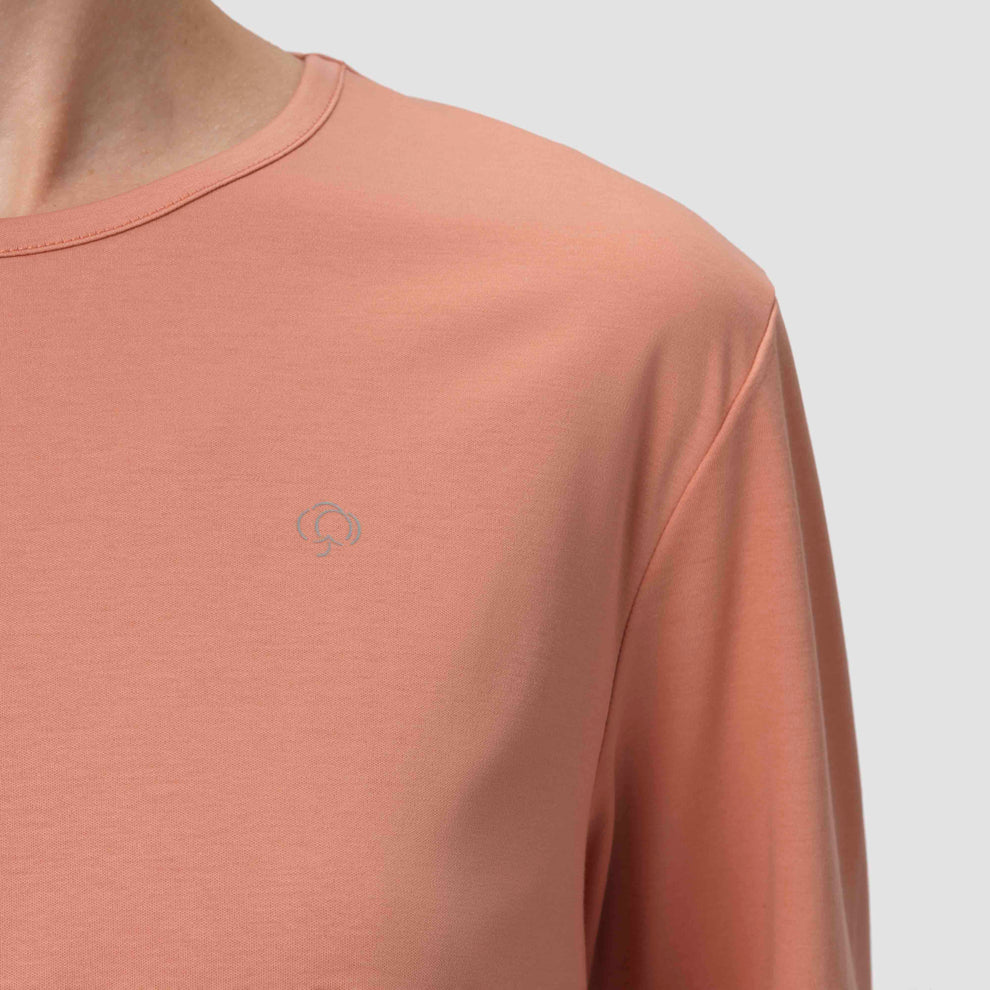 Gros plan sur un pyjama à manches longues de couleur terracotta orné d'un logo argenté