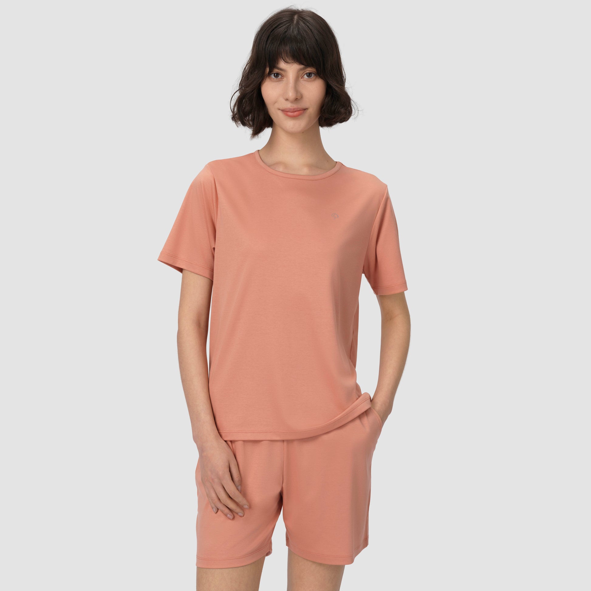 Person wearing a matching pink t-shirt and shorts set on a plain background