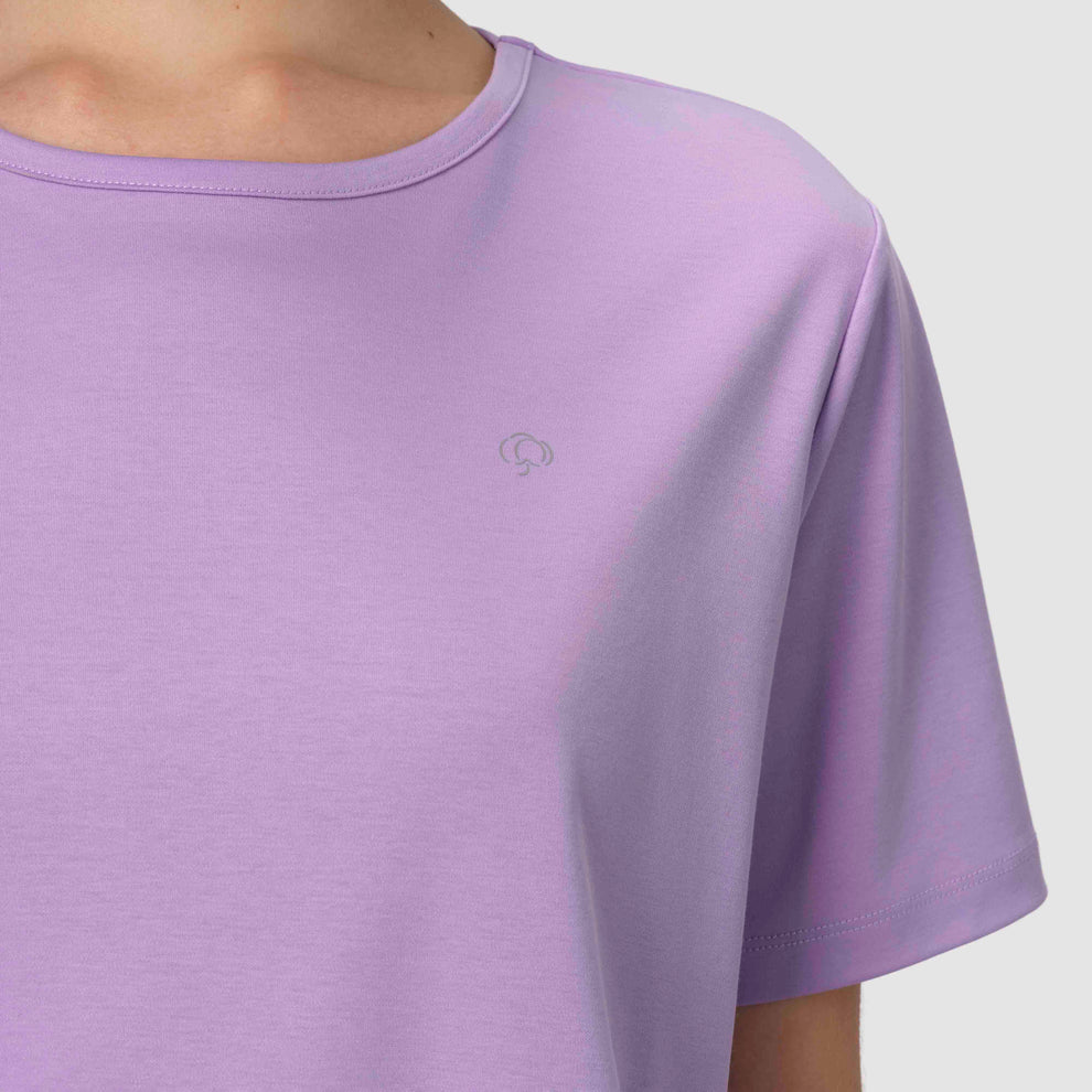 Gros plan sur le haut d'un pyjama couleur lavande, orné d'une fleur en coton argenté