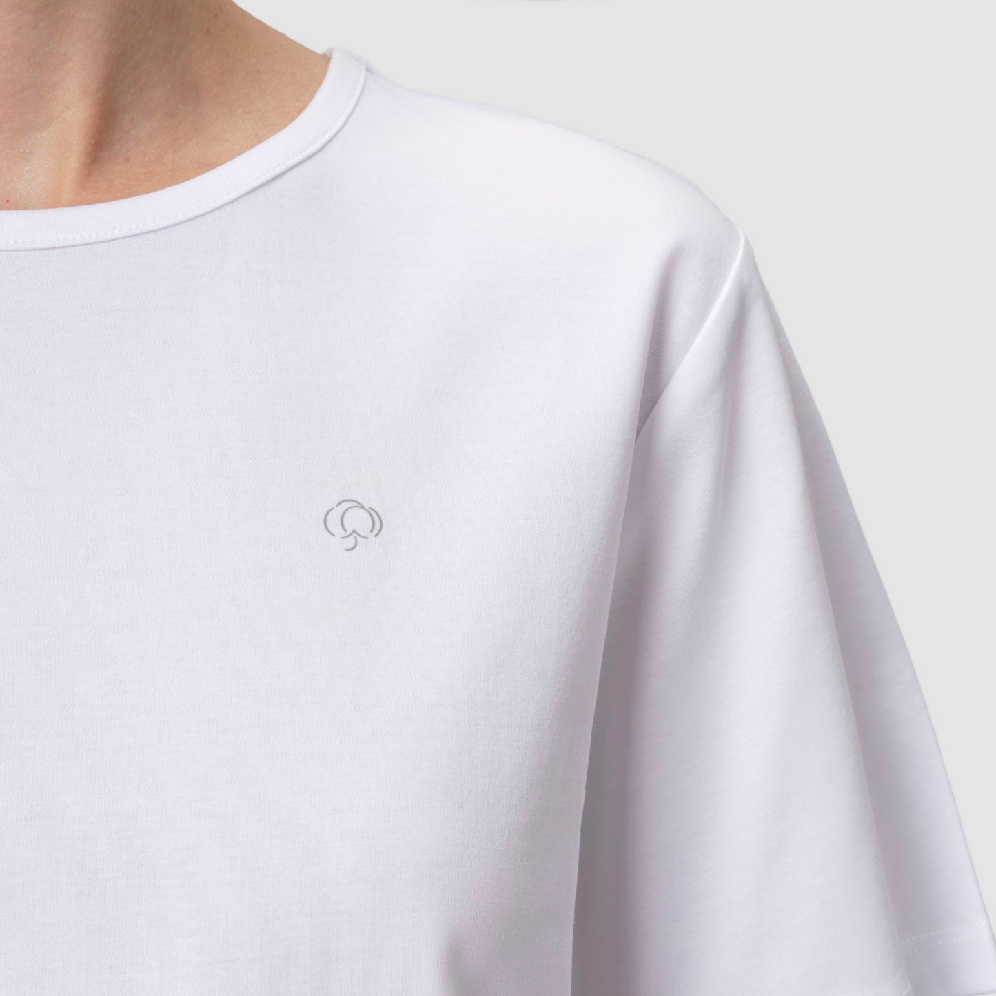 White t-shirt with a small logo on a plain background