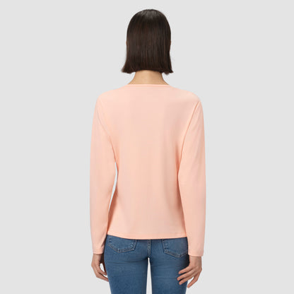 Person wearing a light pink shirt and blue jeans on a plain background