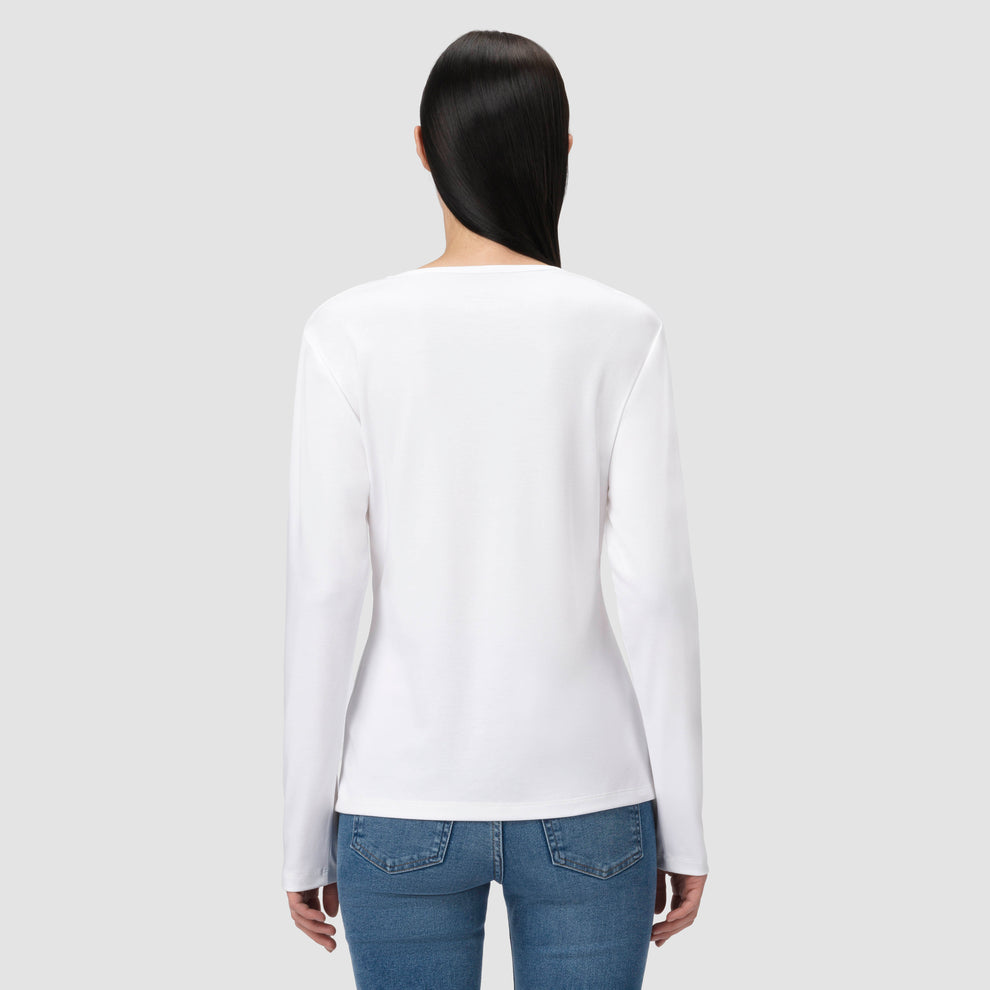 Une personne vêtue d'une chemise blanche à manches longues et d'un jean bleu sur un fond gris clair