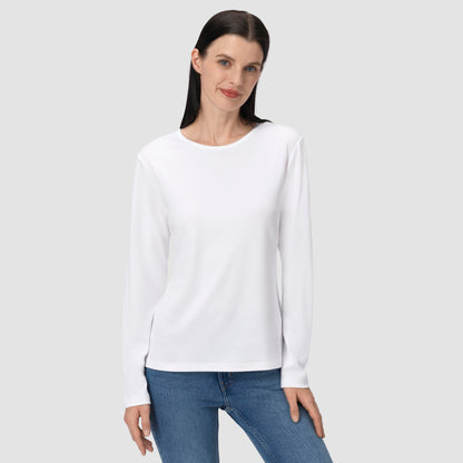 Woman wearing a white long-sleeve shirt and blue jeans on a light gray background