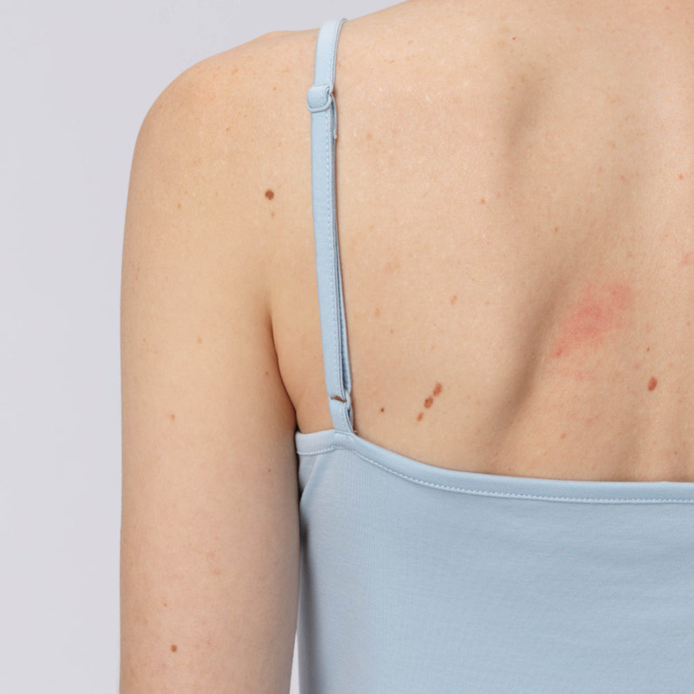 Haut bleu clair à bretelles fines porté par une personne sur un fond uni