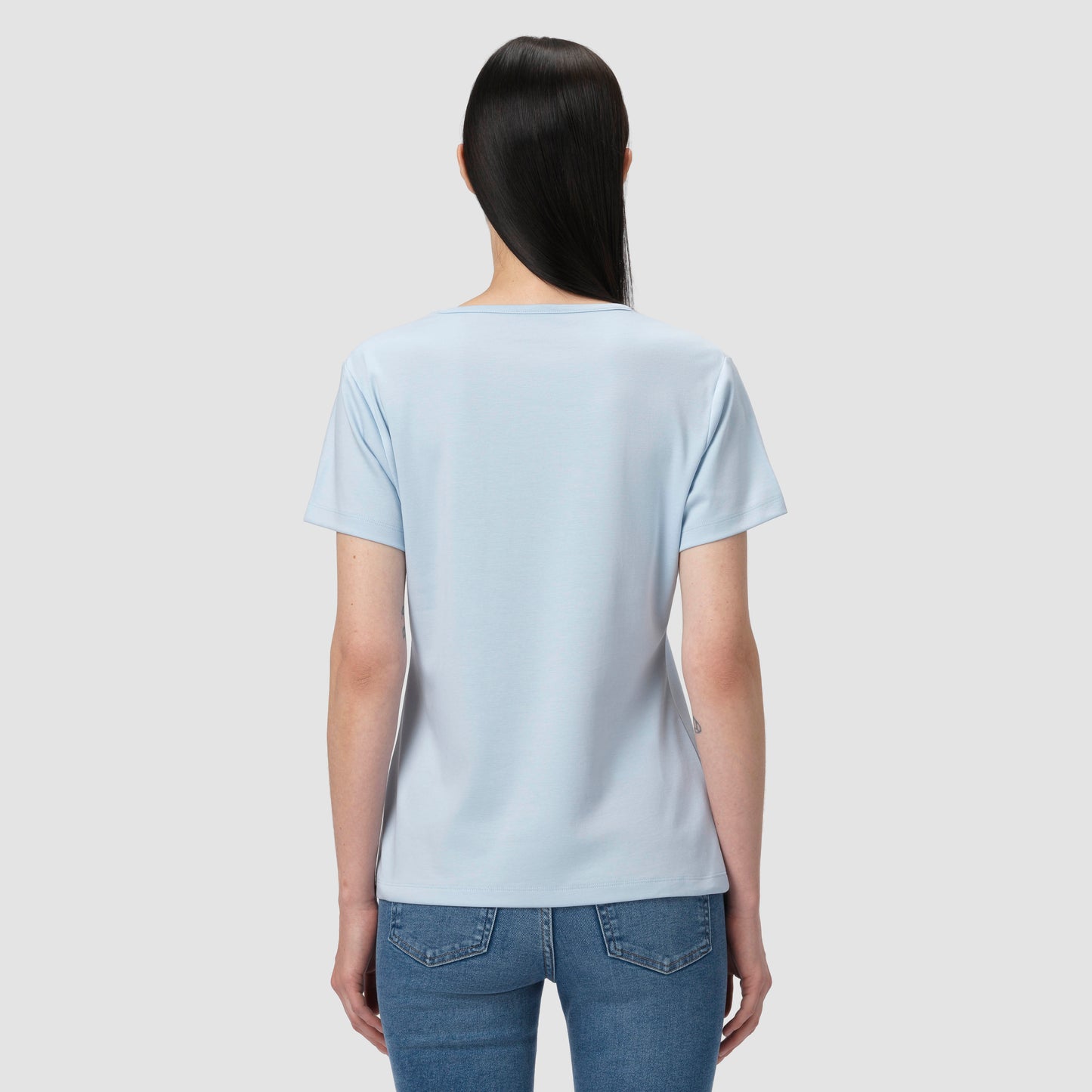 Person wearing a light blue t-shirt and jeans on a plain background