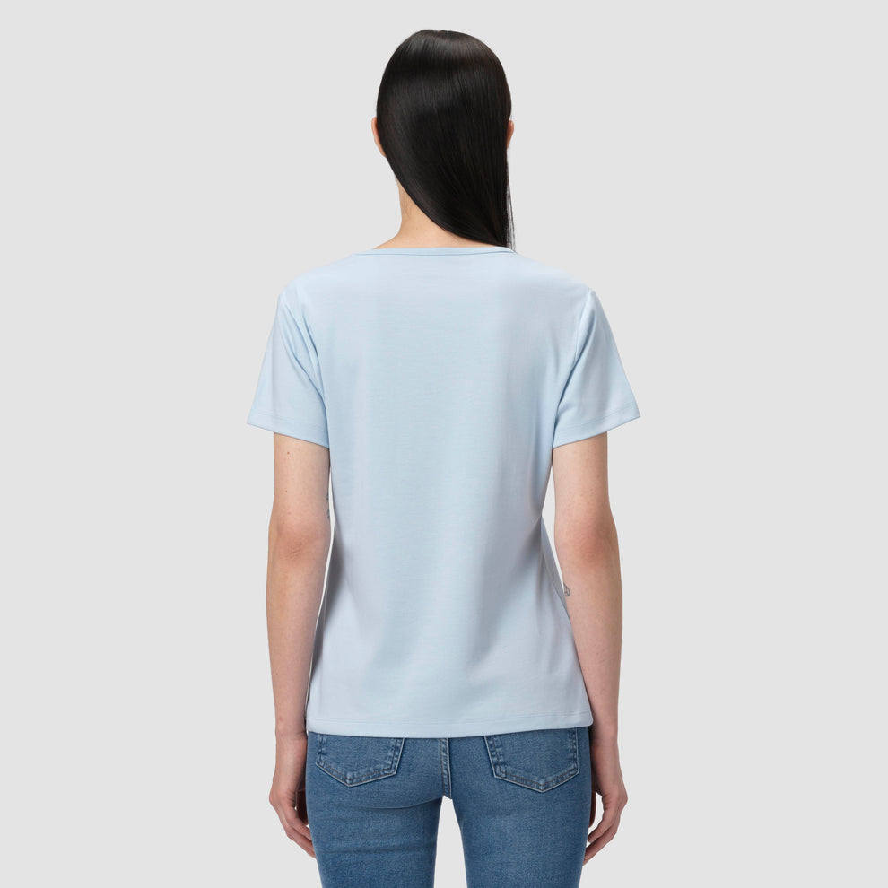 Une personne vêtue d'un t-shirt bleu clair et d'un jean sur un fond uni