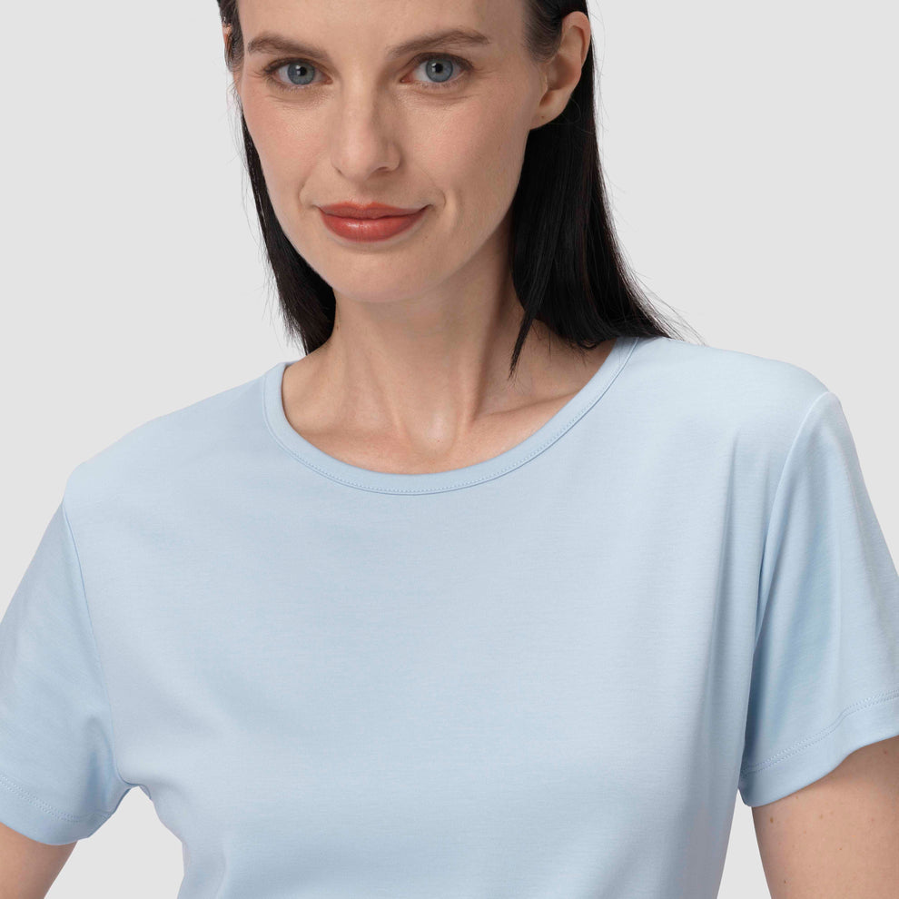 Une femme vêtue d'un t-shirt bleu clair sur un fond uni